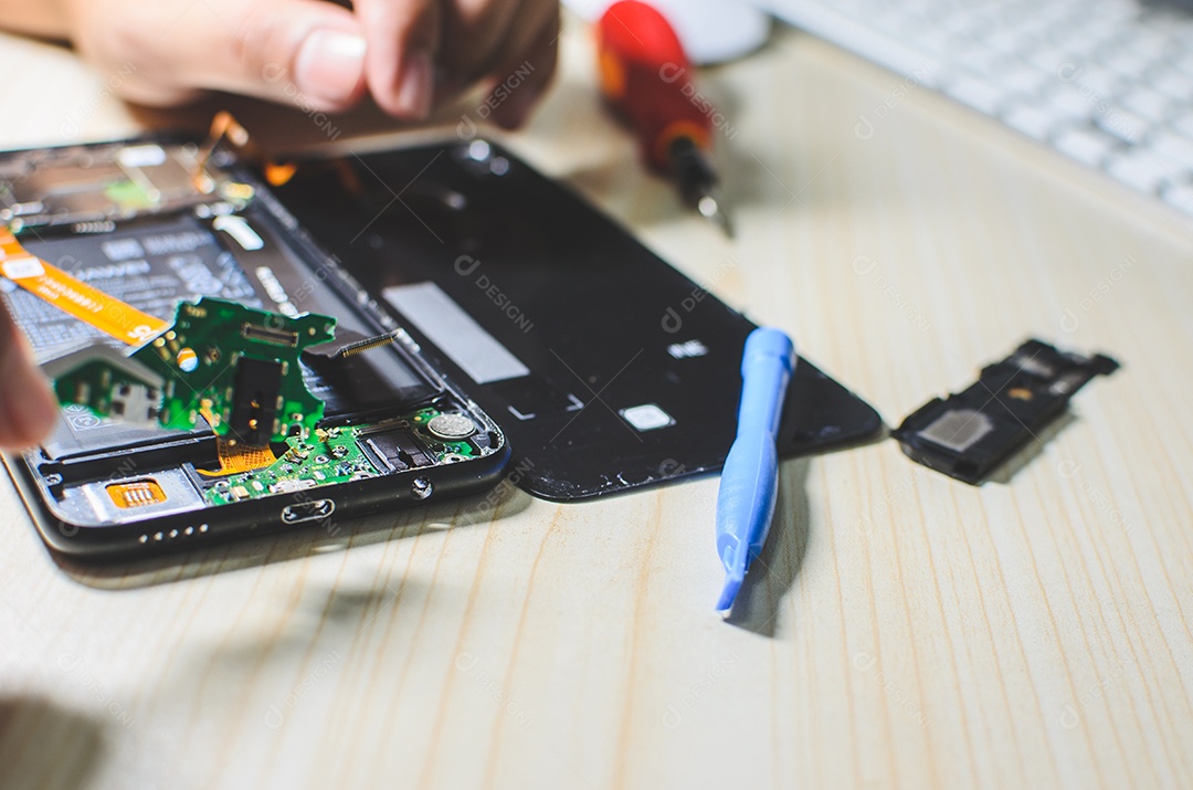 Homem está consertando um telefone celular.
