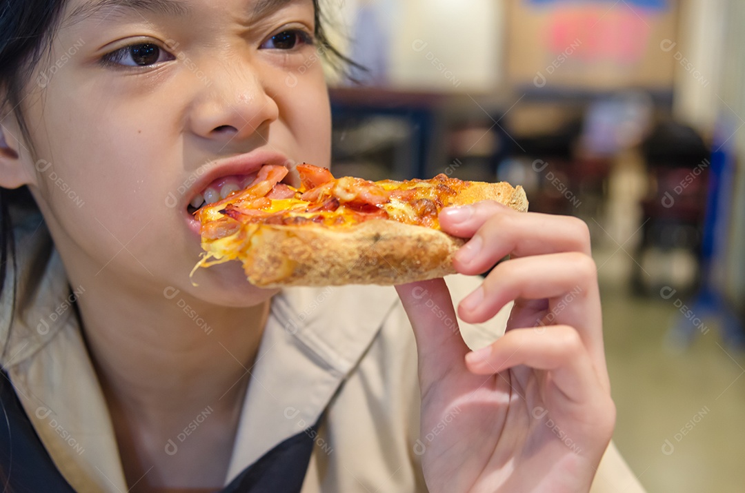 Lindo menino asiático comendo pizza no restaurante.