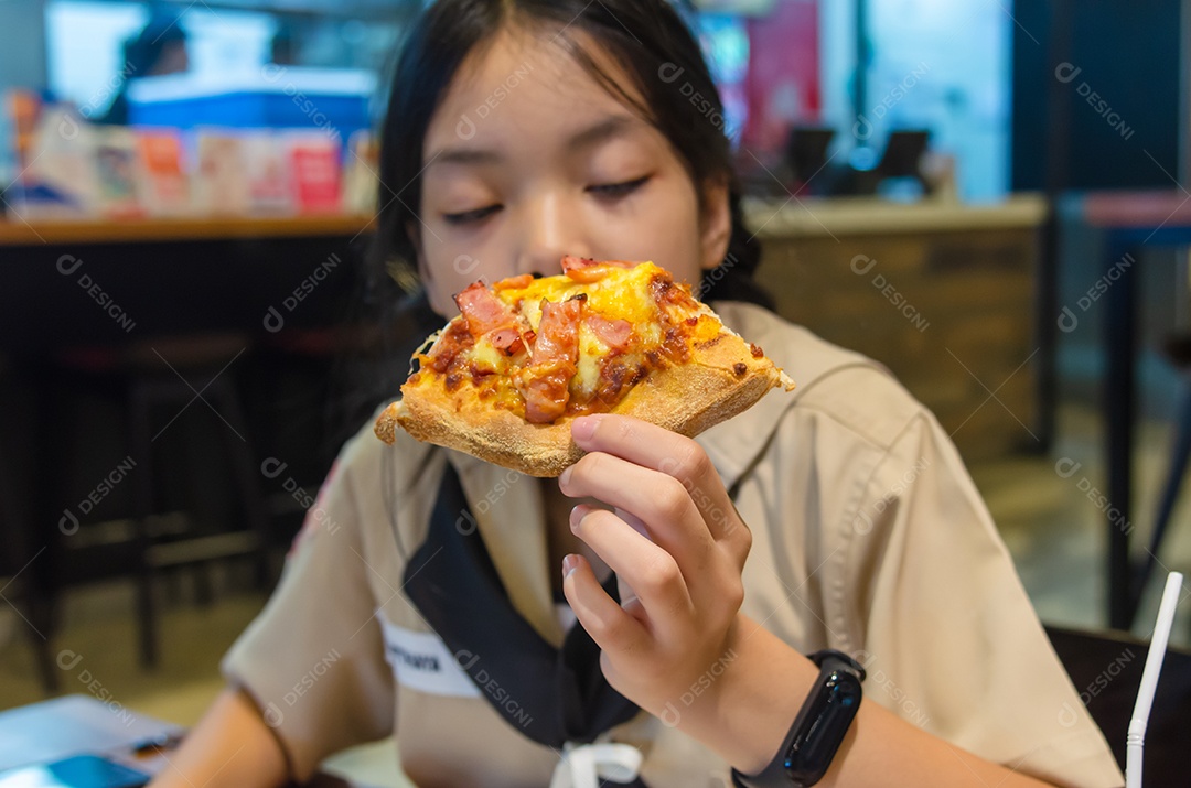 Lindo menino asiático comendo pizza no restaurante.