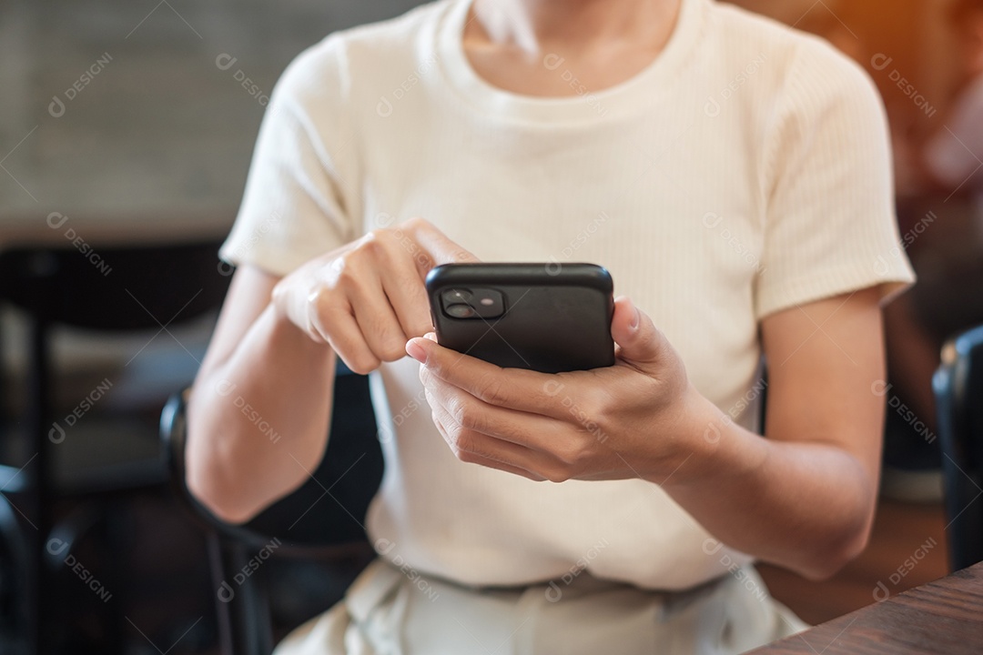 Mulher de negócios casual segurando e usando smartphone para mensagens sms, jovem digitando celular touchscreen no café ou escritório moderno. estilo de vida, tecnologia, mídia social e conceito de rede
