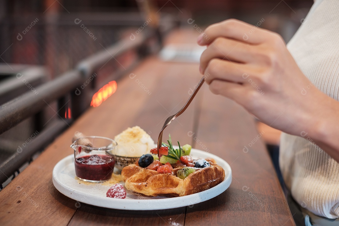 Mulher comendo sobremesa com frutas frescas e frutas no café