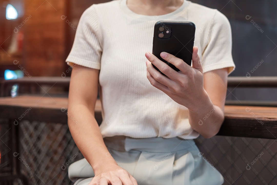 Mulher de negócios casual segurando e usando smartphone para mensagens sms, jovem digitando celular touchscreen no café ou escritório