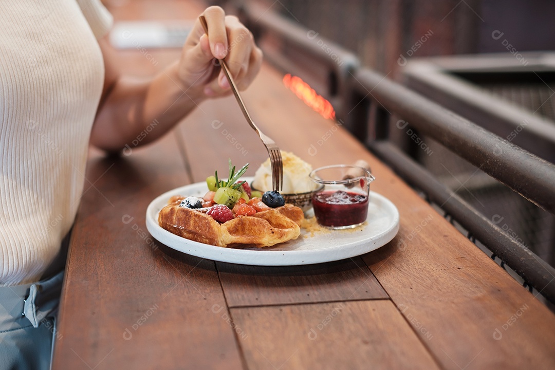 Mulher comendo sobremesa com frutas frescas e frutas no café