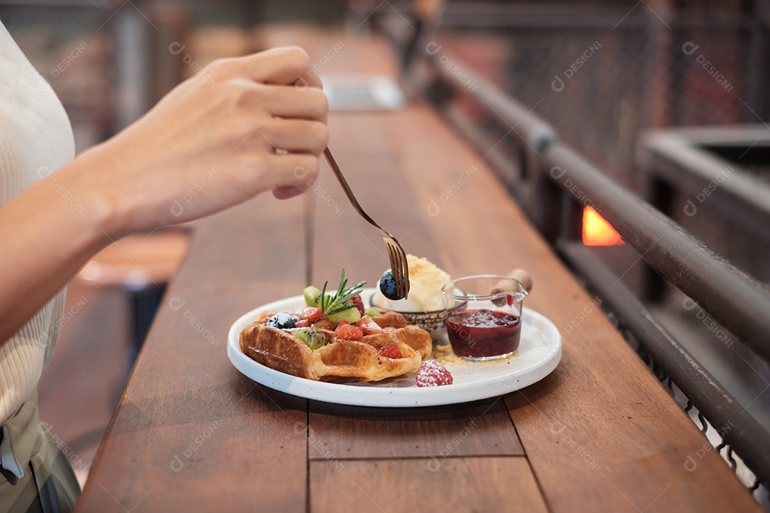Mulher comendo sobremesa com frutas frescas e frutas no café