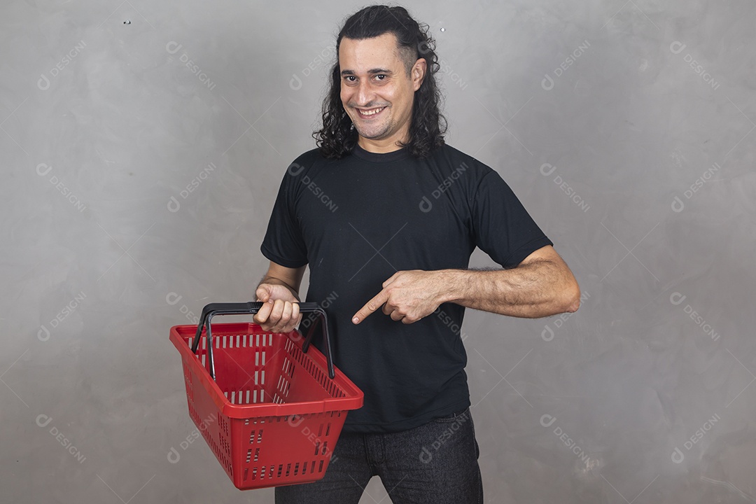 Homem jovem garoto sorridente segurando cesta mercado compras sobre fundo isolado cinza