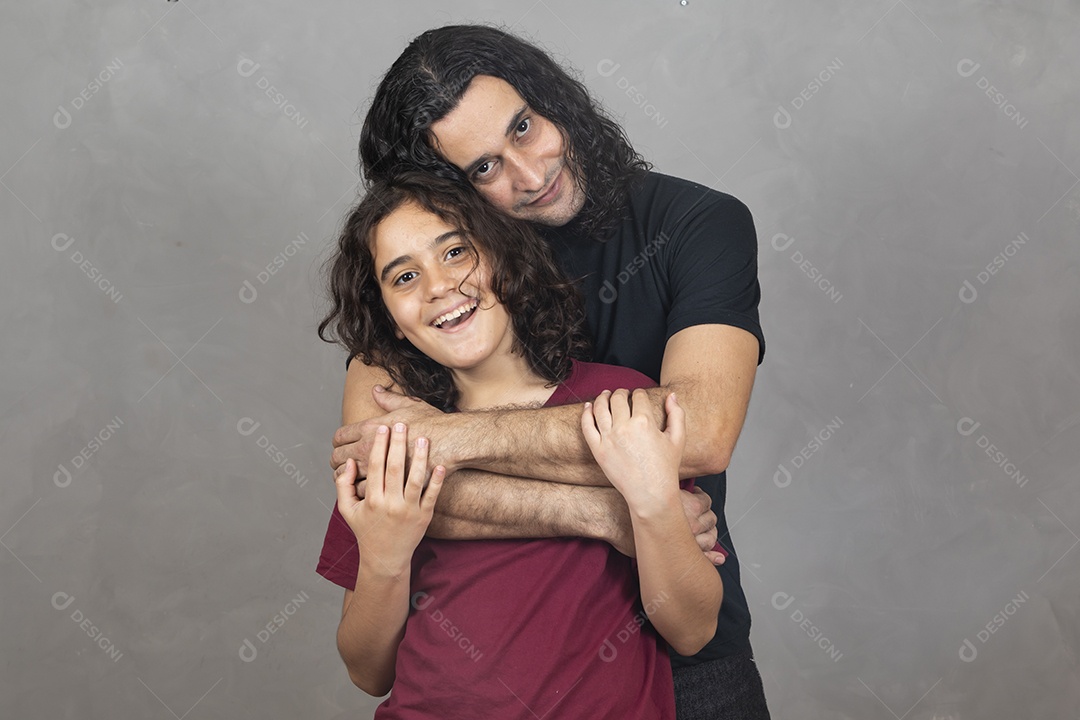 Pai abraçando sua filha sobre fundo cinza