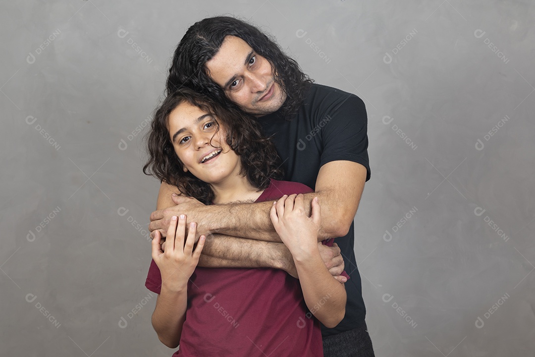 Pai abraçando sua filha sobre fundo cinza