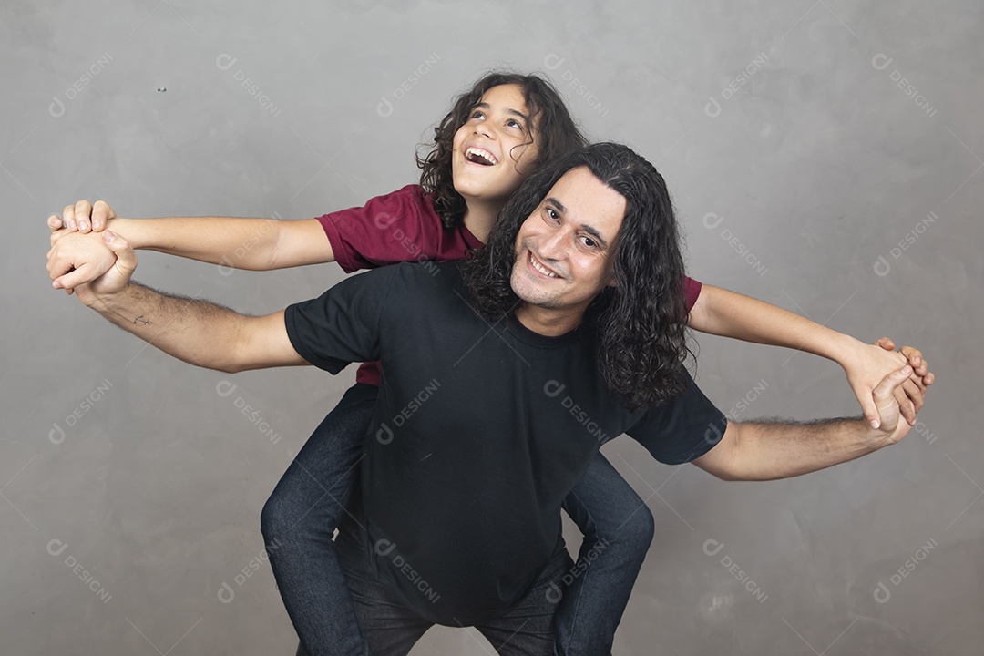 Pai com sua filha nas sua costas sobre fundo cinza