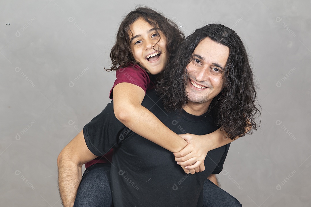 Pai com sua filha nas sua costas sobre fundo cinza