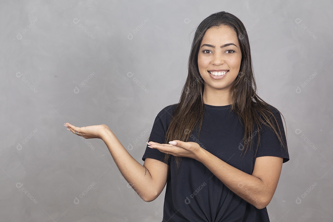 Linda mulher sorridente sobre fundo cinza apontando para lado