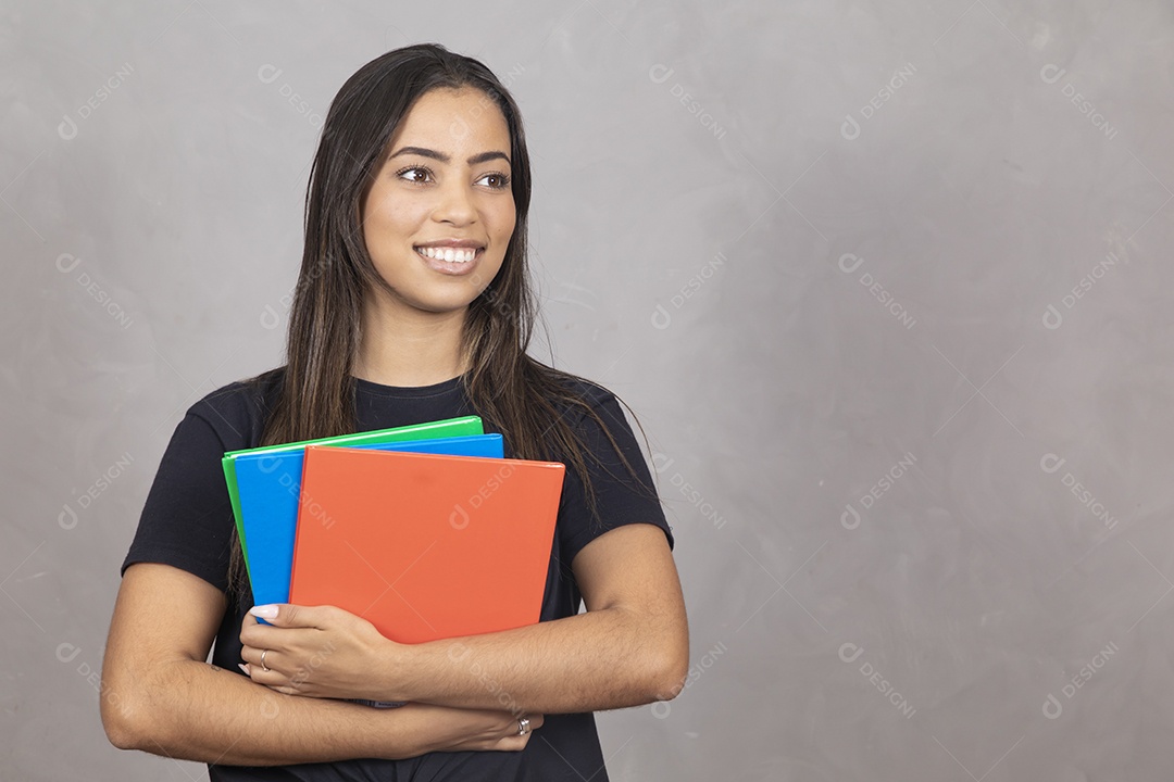 Linda mulher jovem garota sorridente segurando materiais escolar sobre fundo isolado cinza