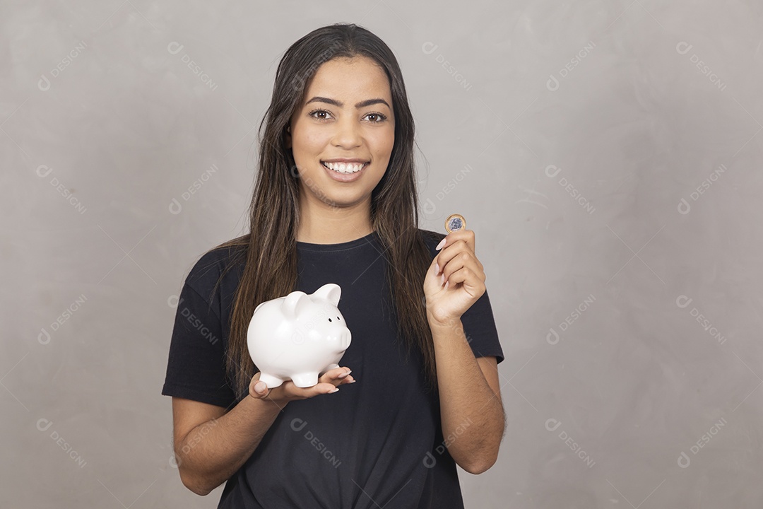 Mulher jovem de camisa preta segurando um cofrinho símbolo de poupança