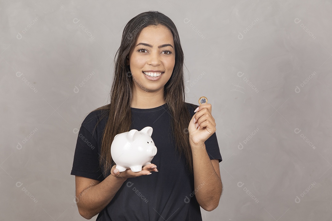 Mulher jovem de camisa preta segurando um cofrinho símbolo de poupança
