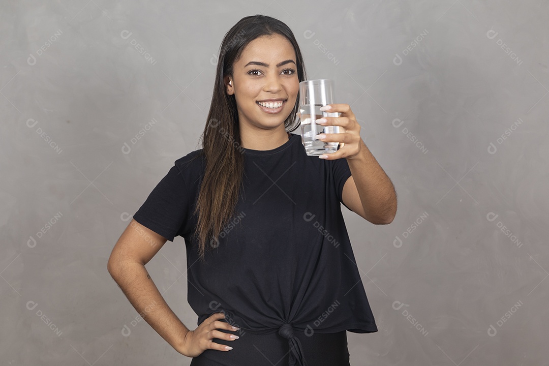 Mulher jovem de camisa preta bebendo um copo de agua