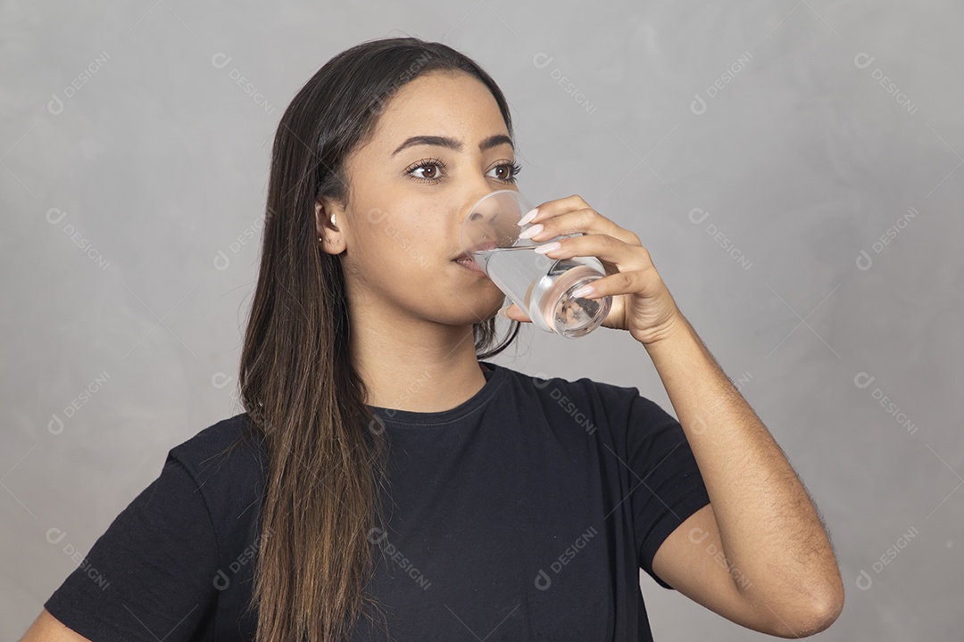 Mulher jovem de camisa preta bebendo um copo de agua
