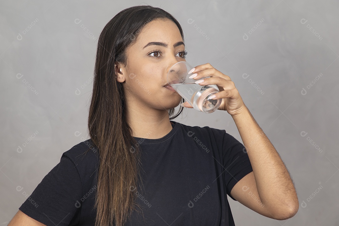 Mulher jovem de camisa preta bebendo um copo de agua