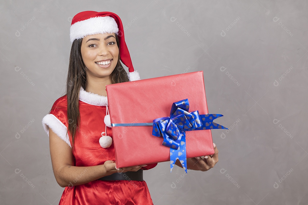 Mulher jovem vestida de Papai Noel segurando um presente