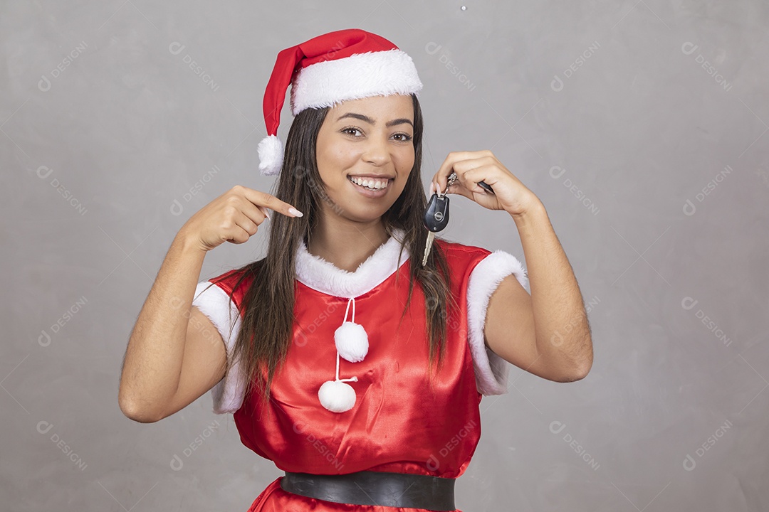 Mulher jovem vestida de Papai Noel segurando um chave de uma automóvel