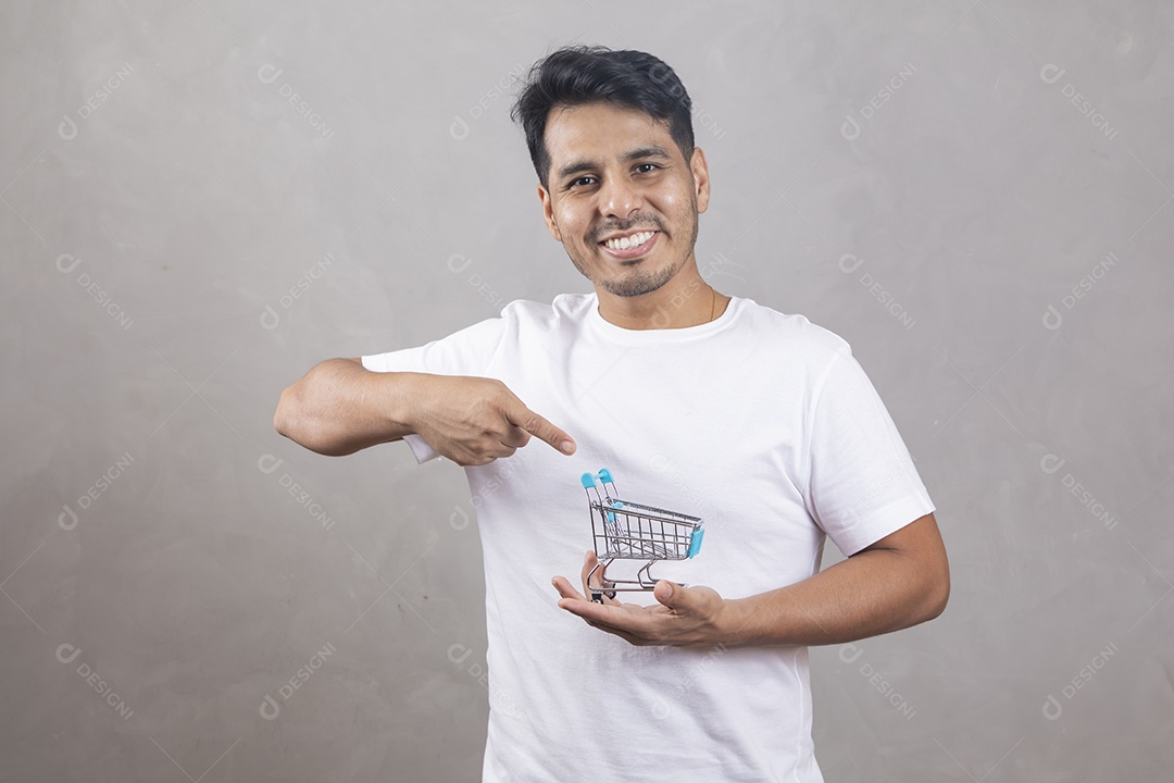 Homem jovem garoto segurando carrinho de compras sorridente sobre fundo isolado cinza