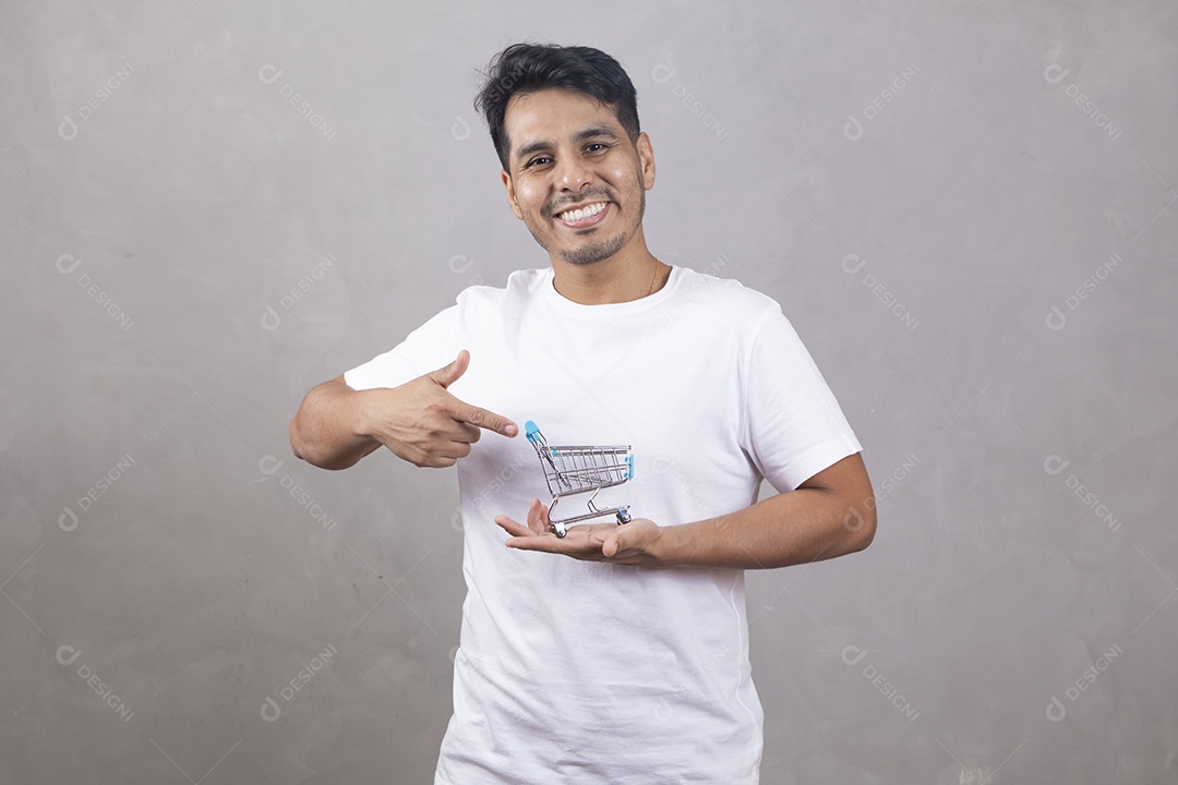 Homem jovem garoto segurando carrinho de compras sorridente sobre fundo isolado cinza