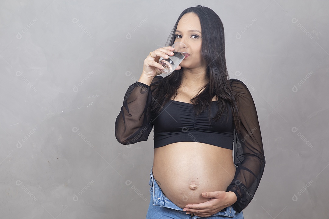 Linda mulher bebendo agua gravida feliz por sua gravidez se hidratando