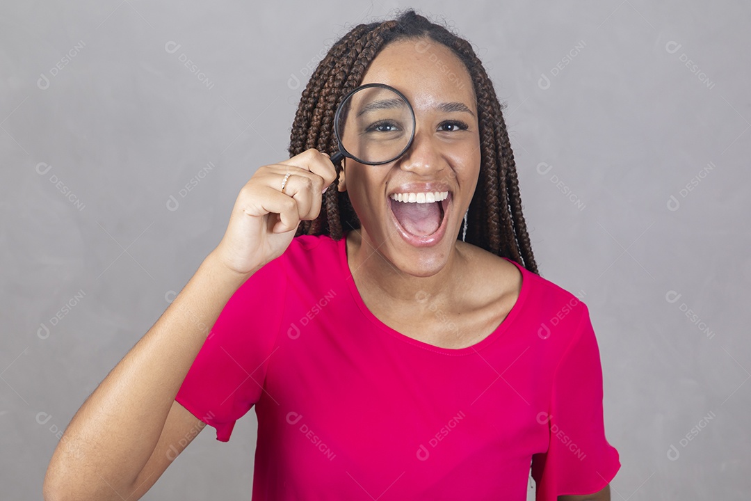 Linda mulher jovem garota sorridente usando lupa sobre fundo isolado cinza