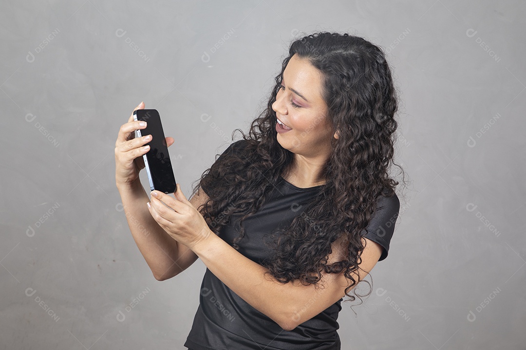 Linda mulher jovem garota sorridente segurando celular sobre fundo isolado cinza