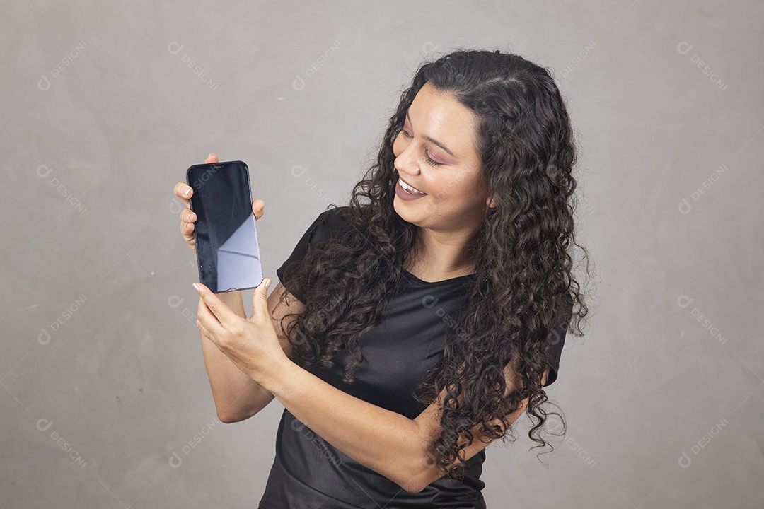 Linda mulher jovem garota sorridente segurando celular sobre fundo isolado cinza