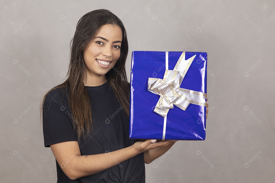 Linda mulher jovem garota sorridente segurando presente sobre fundo isolado cinza