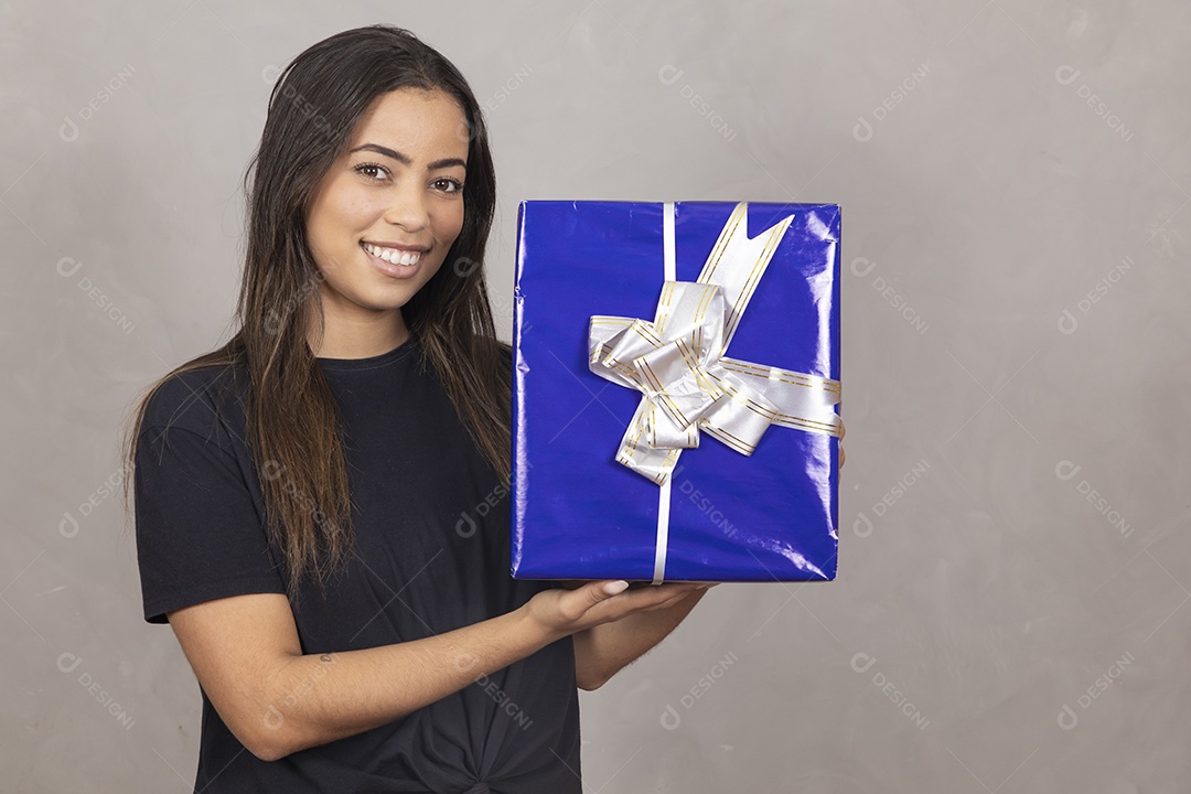 Linda mulher jovem garota sorridente segurando presente sobre fundo isolado cinza