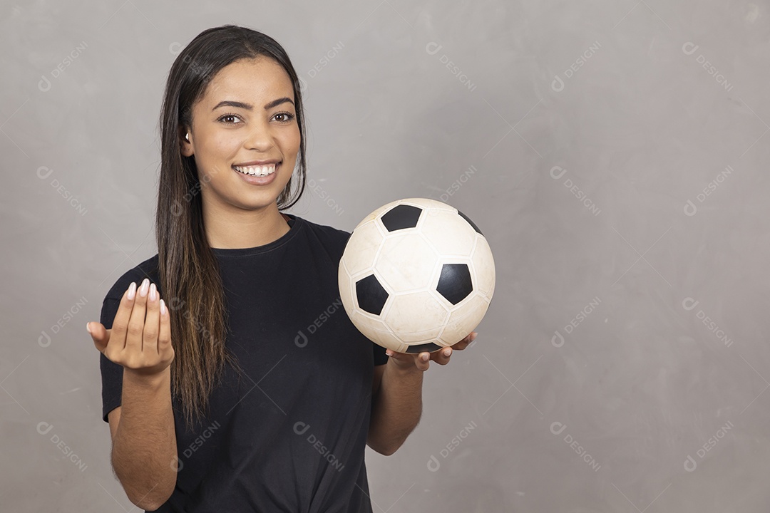 Linda mulher jovem garota sorridente segurando bola de futebol sobre fundo isolado cinza