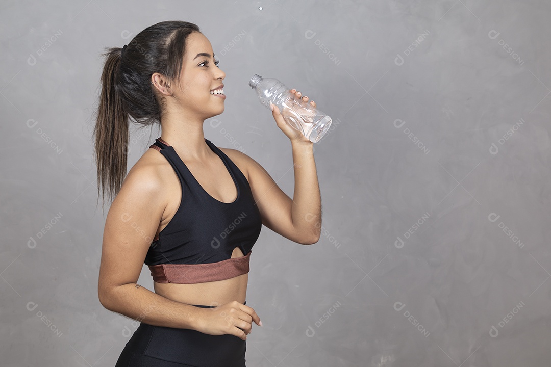 Linda mulher jovem garota bebendo agua sorridente sobre fundo isolado cinza