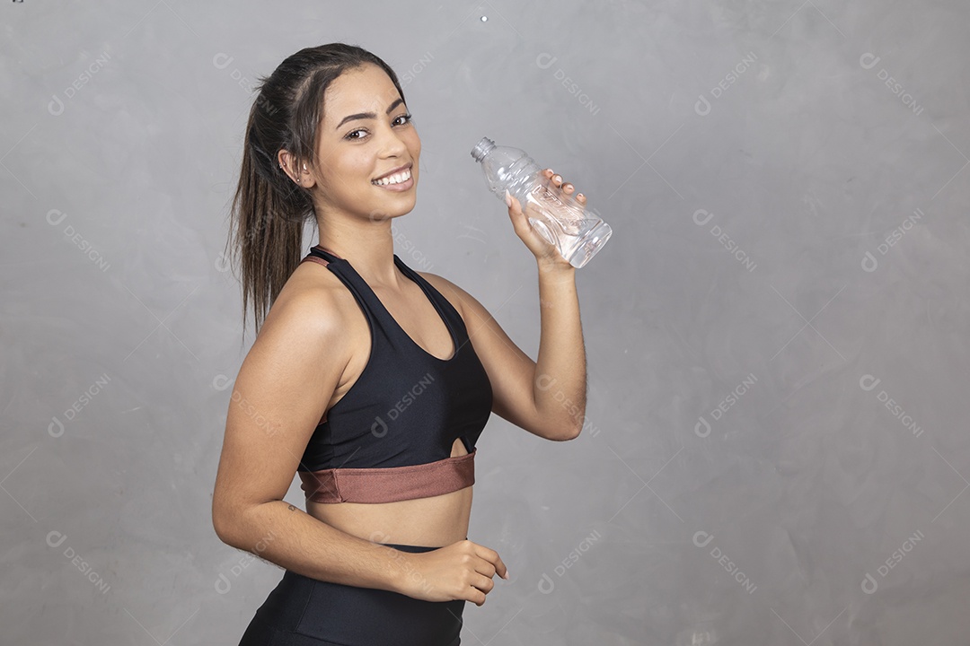 Linda mulher jovem garota bebendo agua sorridente sobre fundo isolado cinza