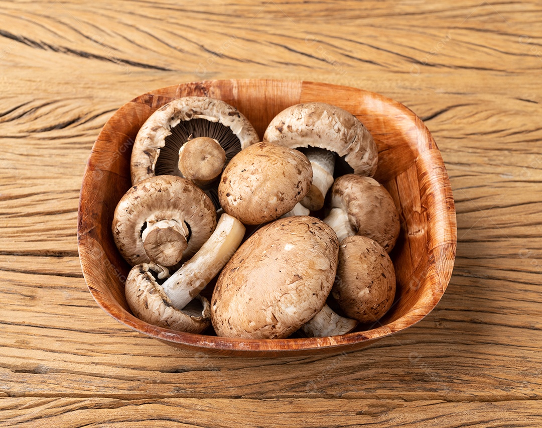 Cogumelos Portobello em uma tigela sobre a mesa de madeira.