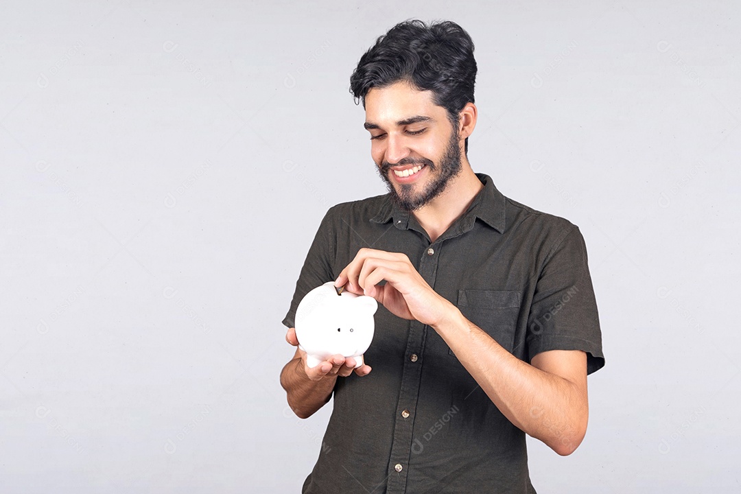 Homem jovem segurando cofrinho guardando dinheiro fundo isolado branco