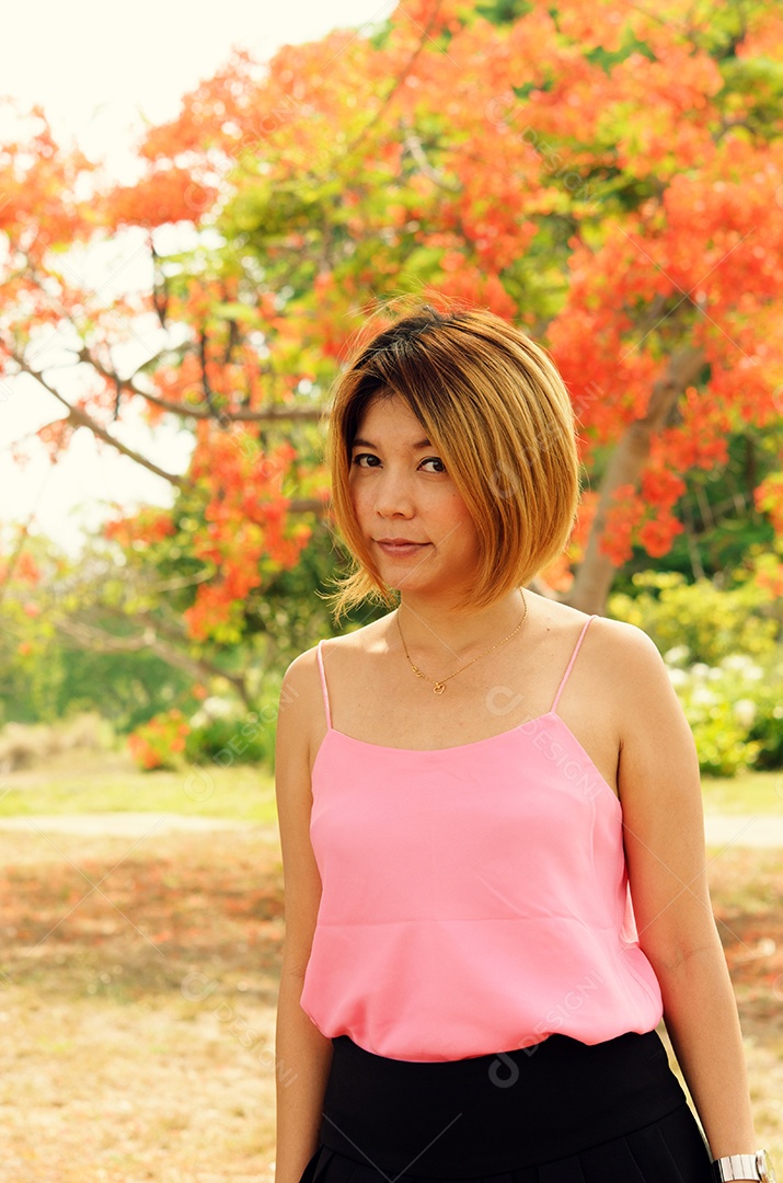 Camisa rosa feminina em pé no jardim.
