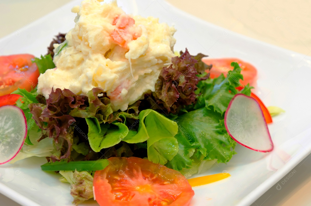 Batata de salada de legumes em um prato branco.