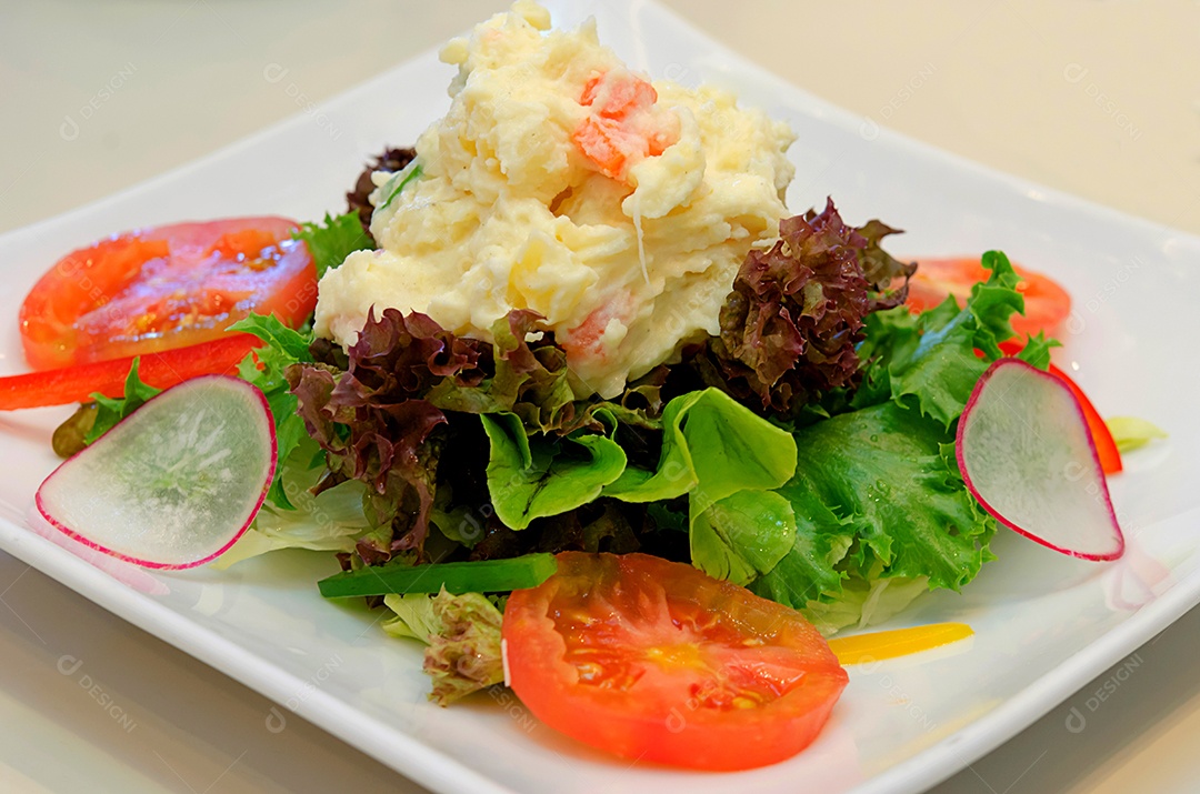 Batata de salada de legumes em um prato branco.