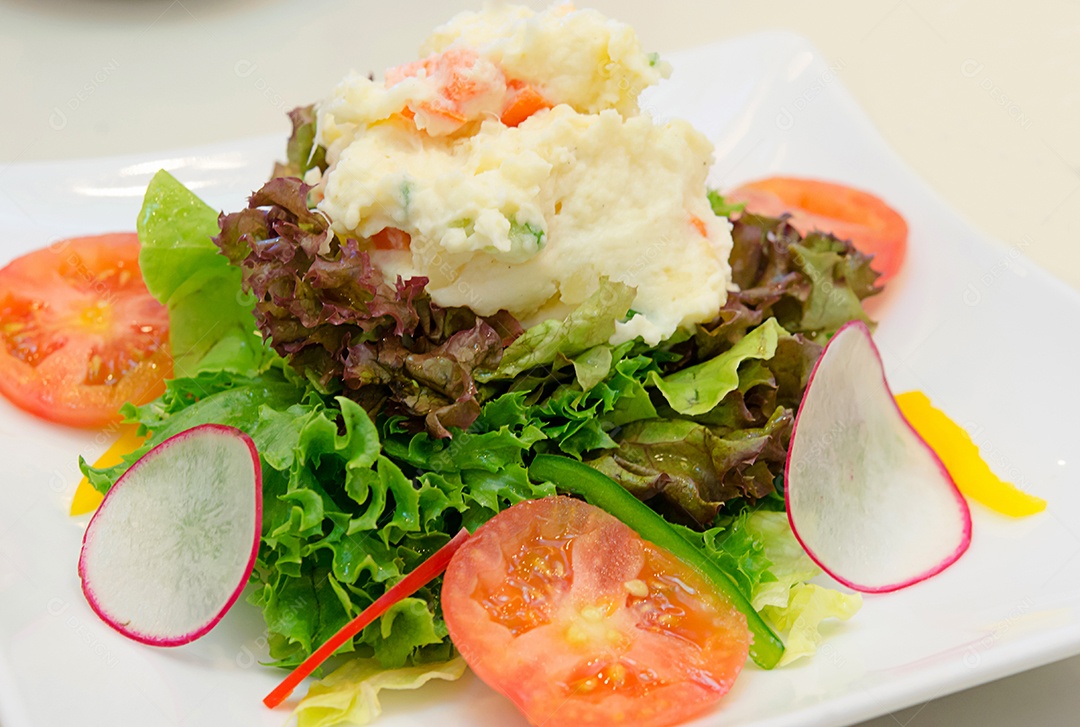 Batata de salada de legumes em um prato branco.