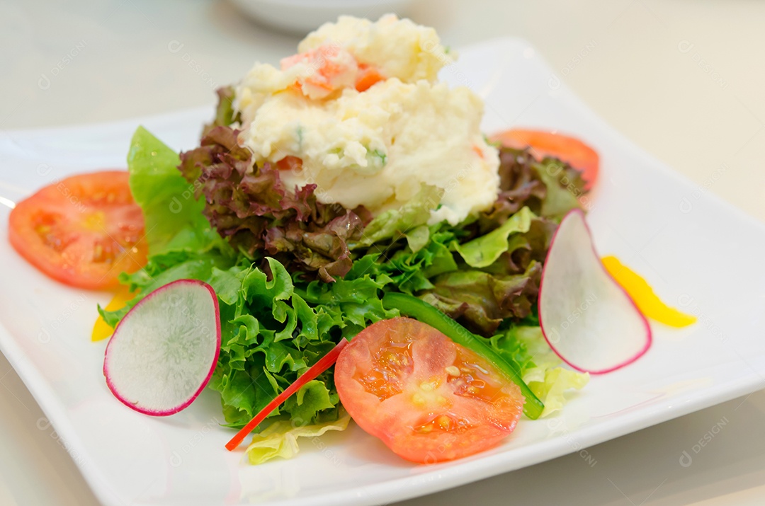 Batata de salada de legumes em um prato branco.