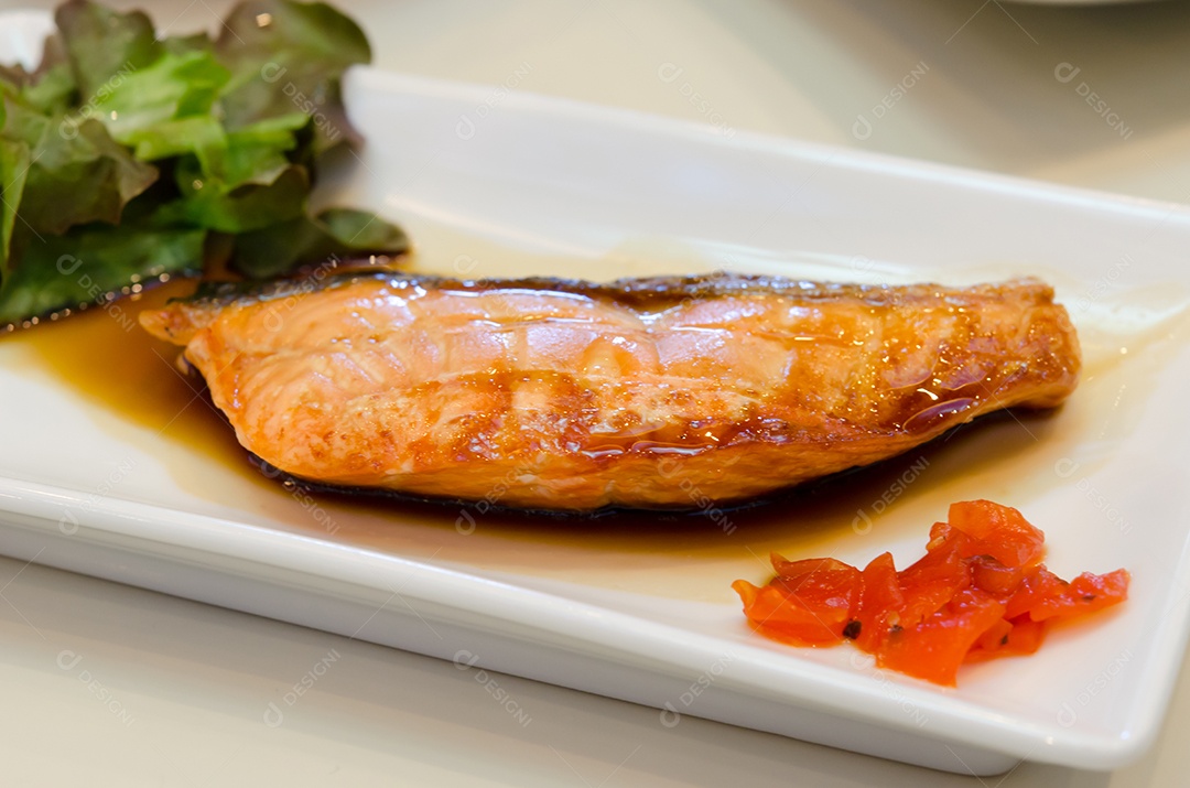Salmão grelhado com molho de soja no prato.