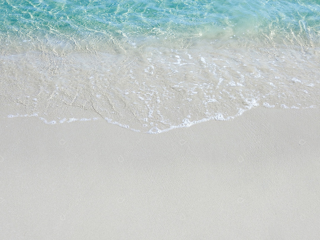 Ondas espumosas em uma praia de areia com água azul do mar em uma praia tropical