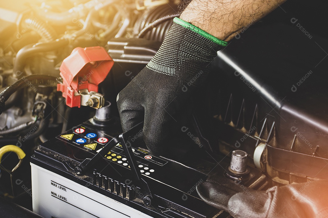 A mão do mecânico está puxando uma bateria de carro velha para substituição