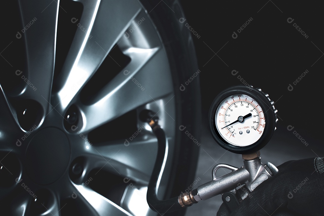 Mecânico testando a pressão dos pneus com um medidor de pressão dos pneus