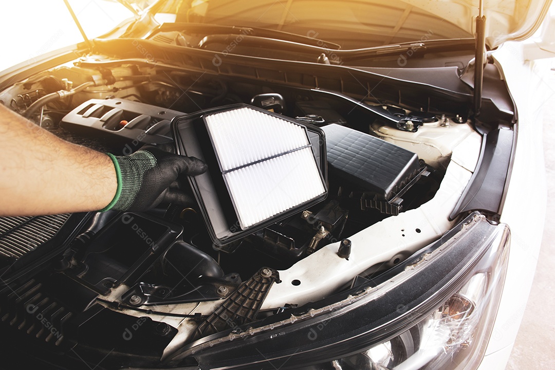 A mão do mecânico é o filtro de ar do carro de substituição no soquete do filtro de um motor de carro com luz solar