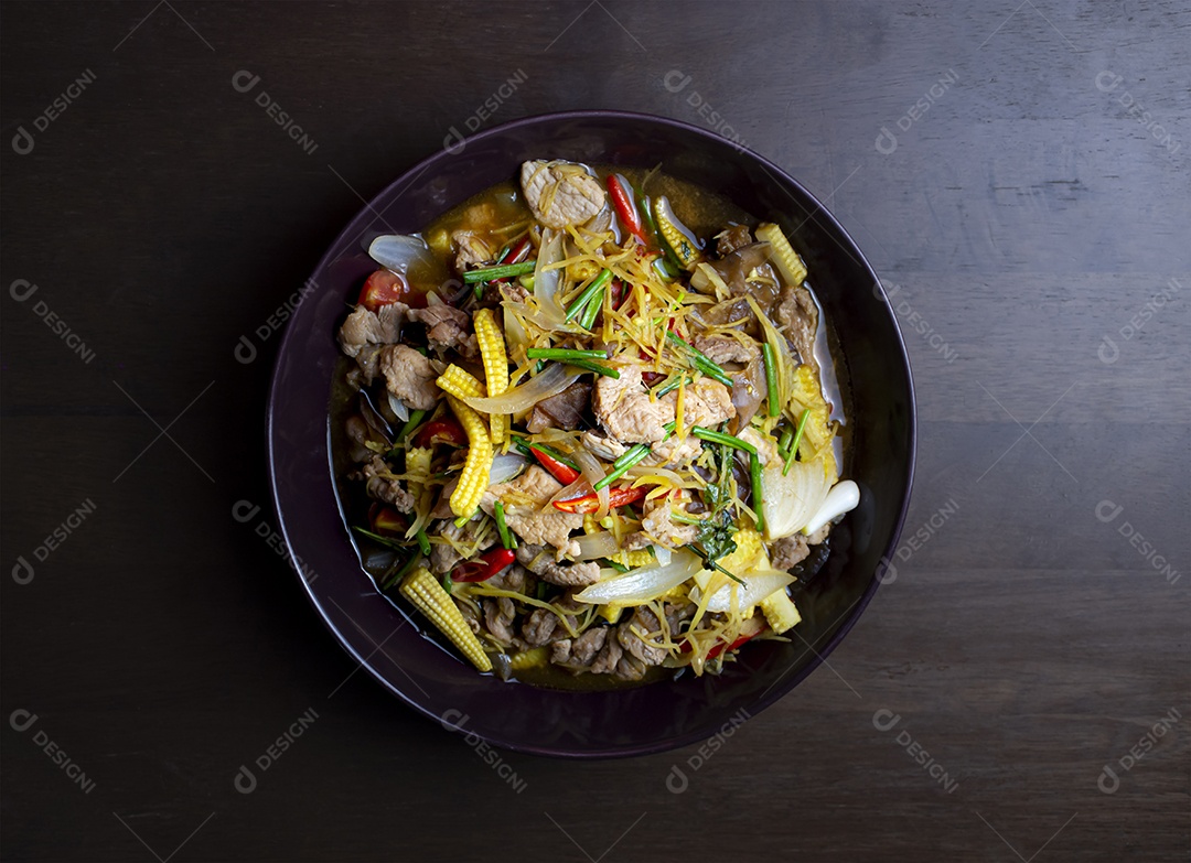 Misture a carne de porco frita e gengibre com legumes misturados em um prato preto sobre uma mesa de madeira