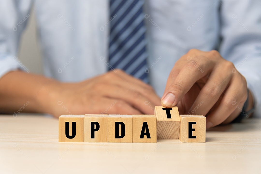 Mão de empresário segurando a atualização de texto de bloco de cubo de madeira no conceito de mesa.