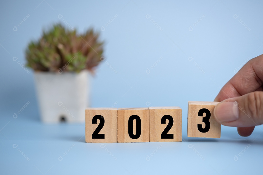 Homem de mão segurando o bloco de cubo de madeira 2023 no fundo.