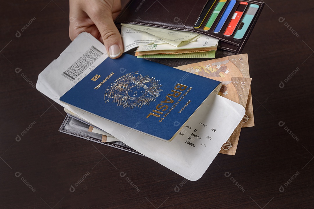 Mão segurando o passaporte brasileiro sobre a mesa.