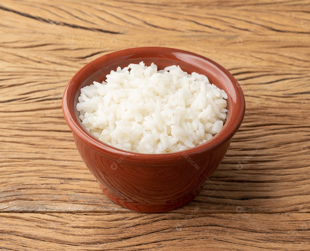 Arroz branco cozido em uma tigela sobre a mesa de madeira.